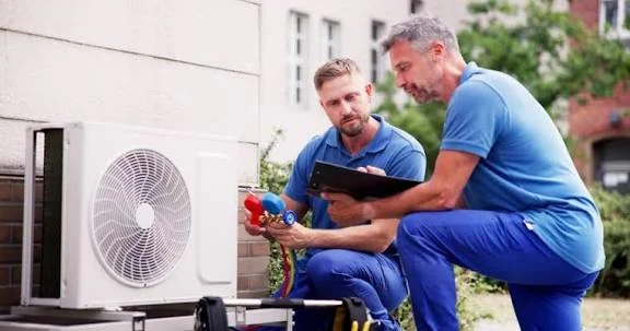Two HVAC technicians evaluating a residential outdoor system