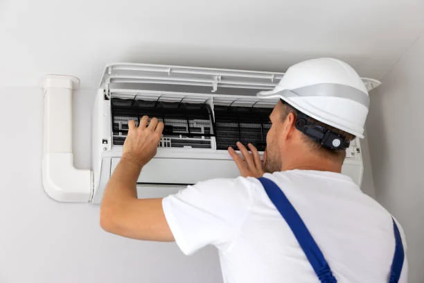 Technician inspecting and cleaning an indoor ductless air conditioning unit
